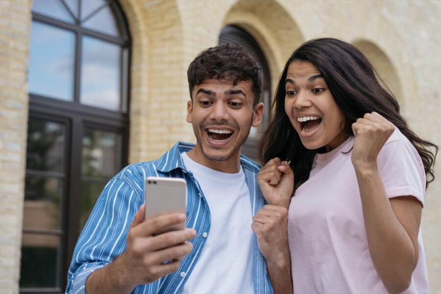 An image depicting a boy and girl smiling while looking at a mobile phone screen.